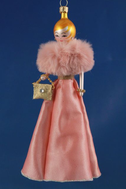 Ёлочная игрушка в виде женщины в розовом платье с меховым воротником и золотистой сумочкой.